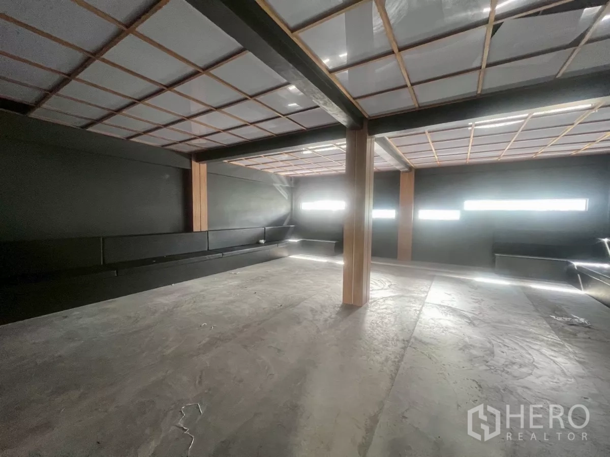 Shophouse for rent in Watthana, Bangkok - Large upper-floor hall with a grid ceiling, narrow windows, and bench seating.