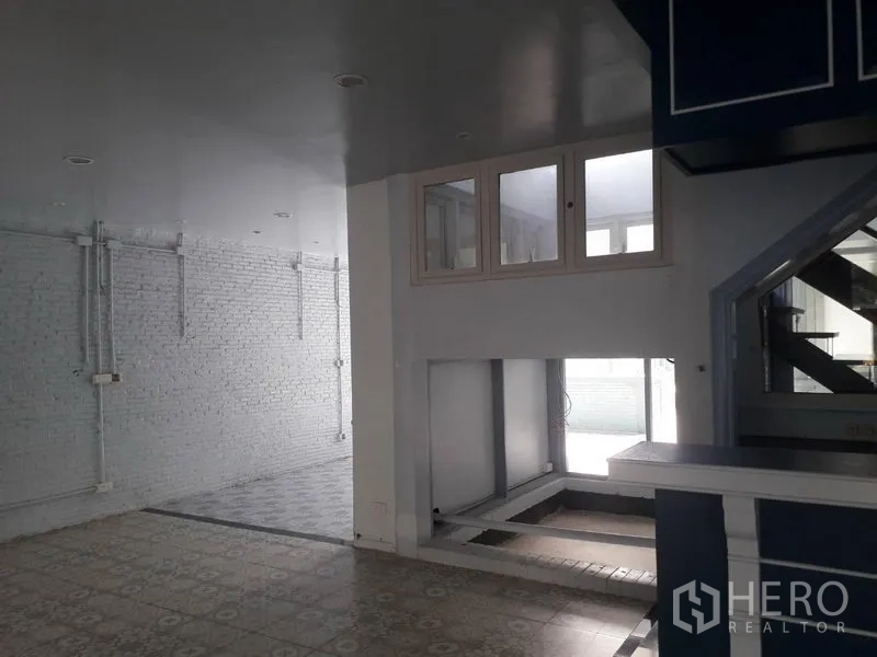 Detached House for rent in Watthana, Bangkok - Loft-style space with painted white brick wall and split-level floor.