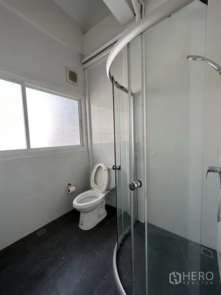 Retail Space for rent in Watthana, Bangkok - Clean bathroom with curved glass shower enclosure, toilet, and frosted window.