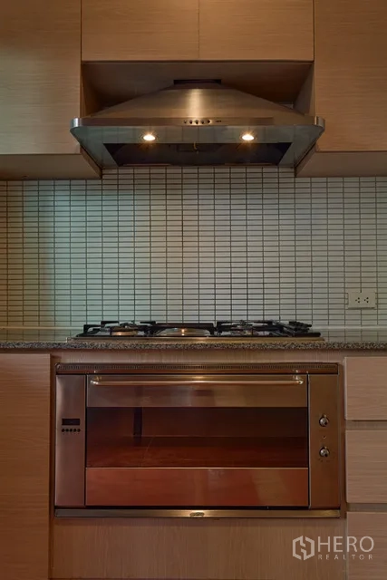 Detached House for rent in Watthana, Bangkok - Modern kitchen featuring gas cooktop, oven and tiled backsplash beneath a range hood.