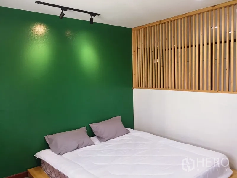 Townhouse for rent in Watthana, Bangkok - Guest bedroom with green wall and wood slat partition.