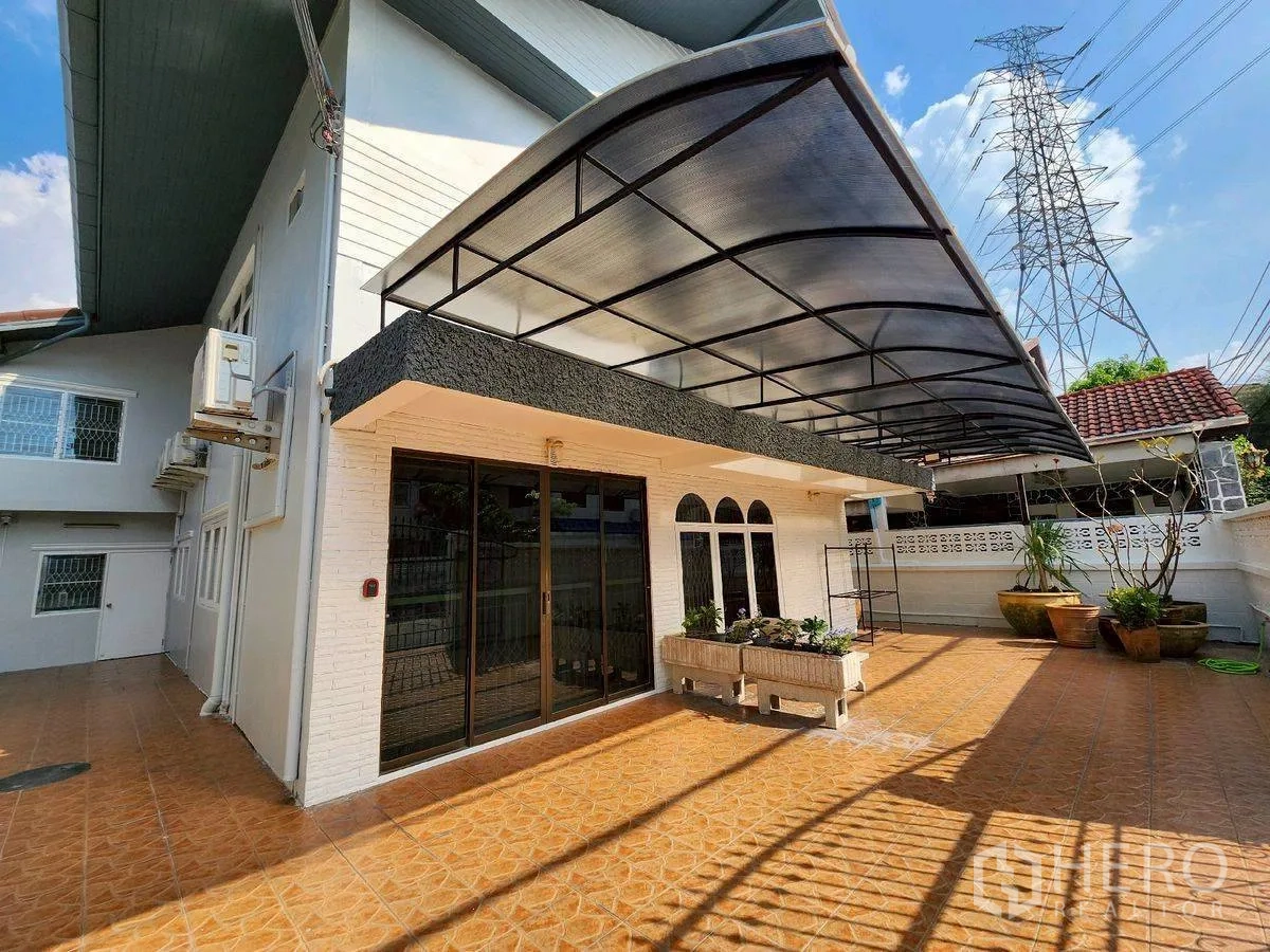 Detached House for rent in Huai Khwang, Bangkok - Front terrace with wide awning, sliding glass doors, and planter boxes.