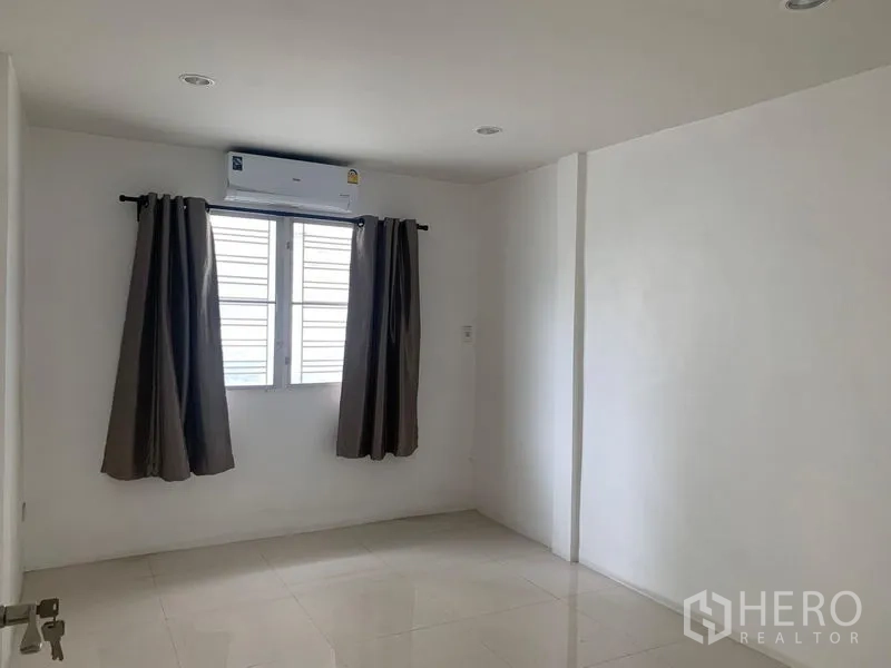 Townhouse for rent in Din Daeng, Bangkok - Second bedroom with tiled floor, AC and natural light from a window.