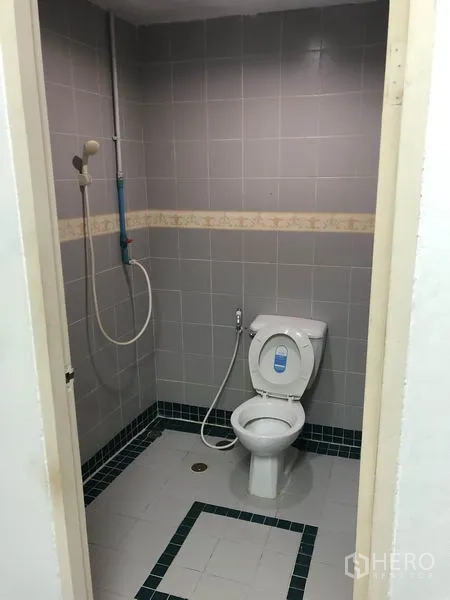 Office Space for rent in Ratchathewi, Bangkok - Compact bathroom with gray tiles, toilet, handheld shower and floor drain.