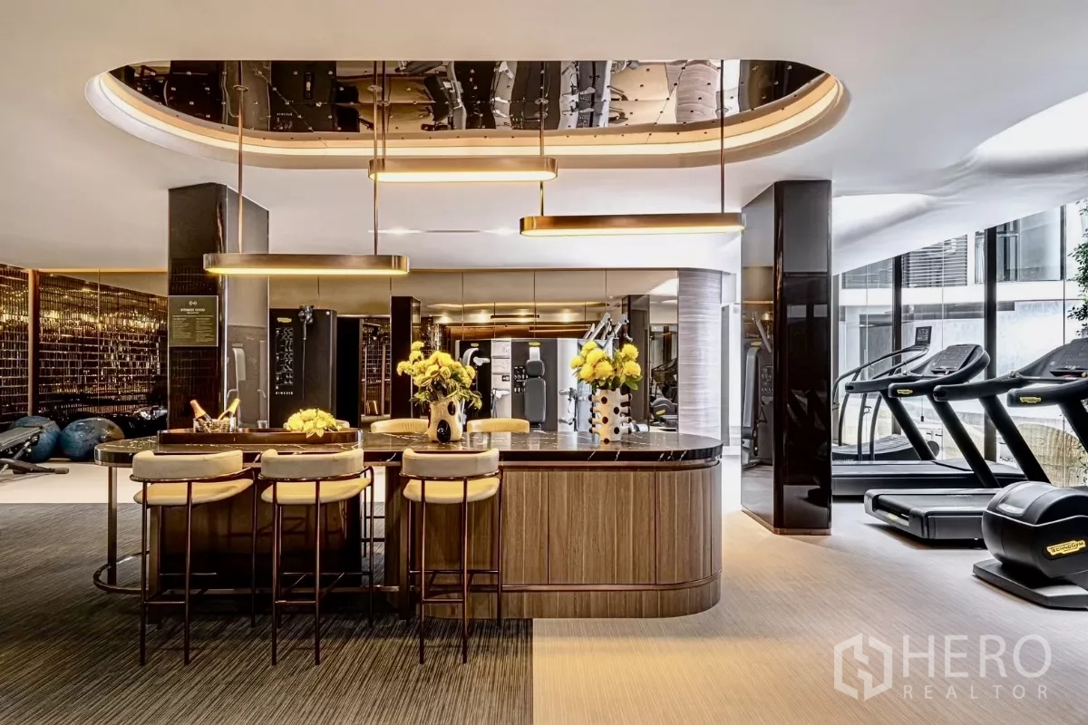 Condominium for rent in Khlong Toei, Bangkok - Fully equipped fitness center with treadmills and training machines beside a lounge bar.