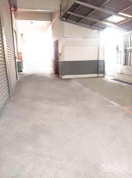 Warehouse for rent in Bang Phli, Samut Prakan - Wide loading alley with roller shutters and a covered roof for truck access.