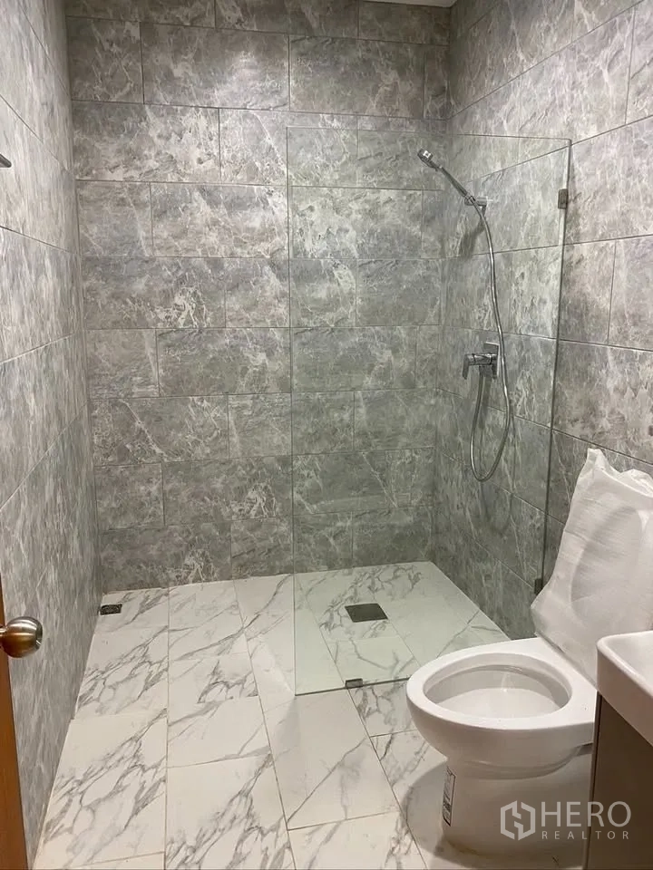 独栋房屋 for rent in Suan Luang, Bangkok - 浴室采用灰色石纹墙面，步入式淋浴与坐便器。