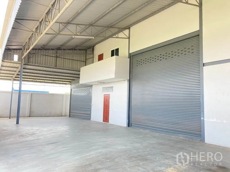 Warehouse for rent in Bang Phli, Samut Prakan - Covered loading bay with steel roof, multiple roller shutter doors and a mezzanine office.