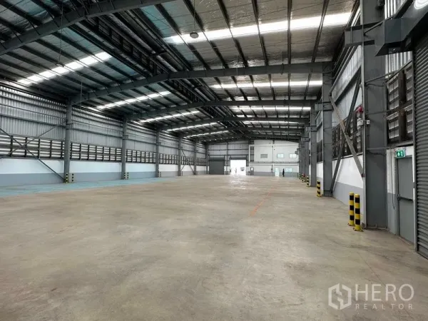 Factory for rent in Mueang Samut Prakan, Samut Prakan - Column-free warehouse space with ventilation panels and safety bollards along the walls.