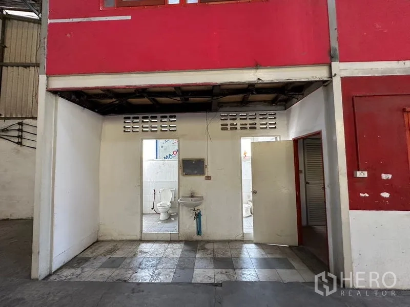 货栈 出租在Suan Luang, Bangkok - 仓库卫生间区域，两个厕位与洗手池，铺设地砖并位于办公室下方。