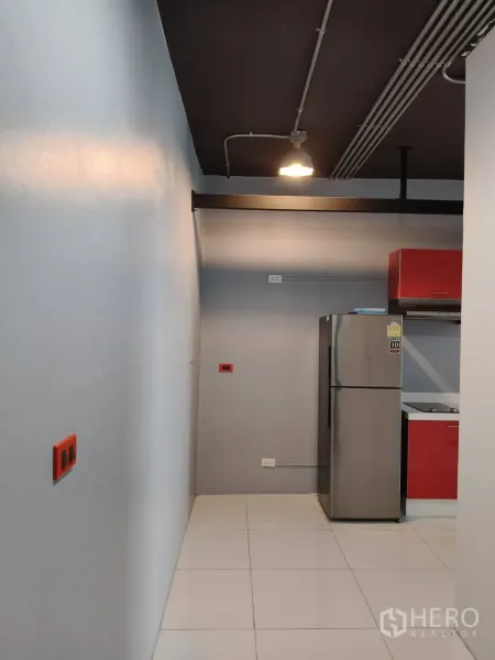 Office Space for rent in Khlong Toei, Bangkok - Narrow corridor with industrial-style exposed ceiling, pendant light, and a kitchenette with a stainless fridge.