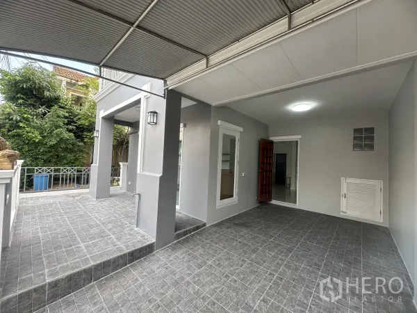 Townhouse for sale in Lam Luk Ka, Pathum Thani - Covered carport and raised front patio with gray floor tiles.