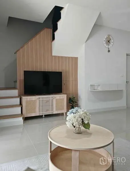 Townhouse for rent in Bang Phli, Samut Prakan - Bright living area with TV console under the staircase, round coffee table and wall clock.