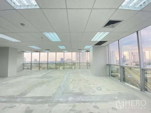 Office Space for rent in Chatuchak, Bangkok - Spacious open-plan office floor with drop ceiling lights and panoramic city vistas through two walls of glass.