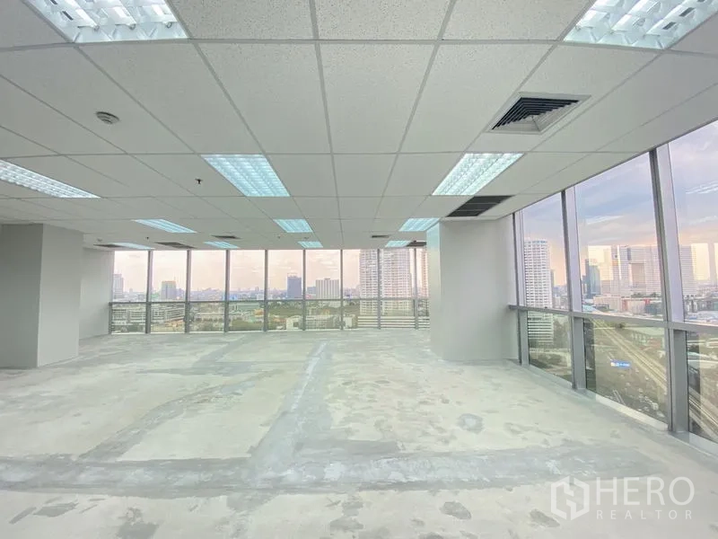 Office Space for rent in Chatuchak, Bangkok - Spacious open-plan office floor with drop ceiling lights and panoramic city vistas through two walls of glass.
