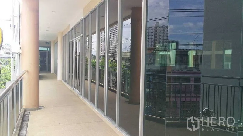 Office Space for rent in Phra Khanong, Bangkok - Glass-fronted exterior of the office along a balcony walkway overlooking the urban skyline.