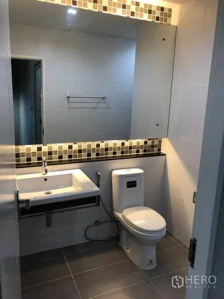 Detached House for rent in Bang Kapi, Bangkok - Contemporary bathroom with large mirror, floating vanity, and tiled walls.