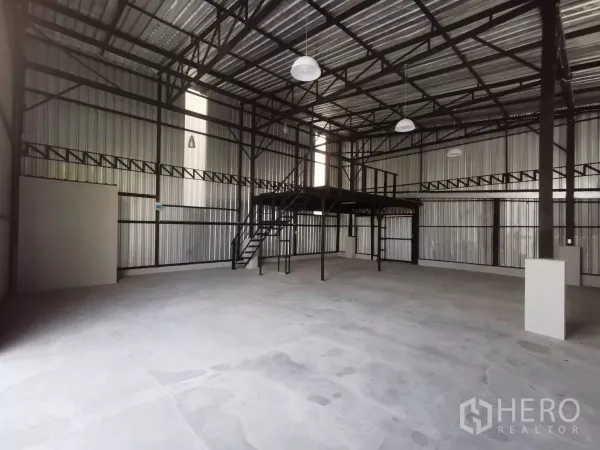 Warehouse for rent in Khlong Toei, Bangkok - Open warehouse floor with metal truss roof, mezzanine platform, and pendant lights.