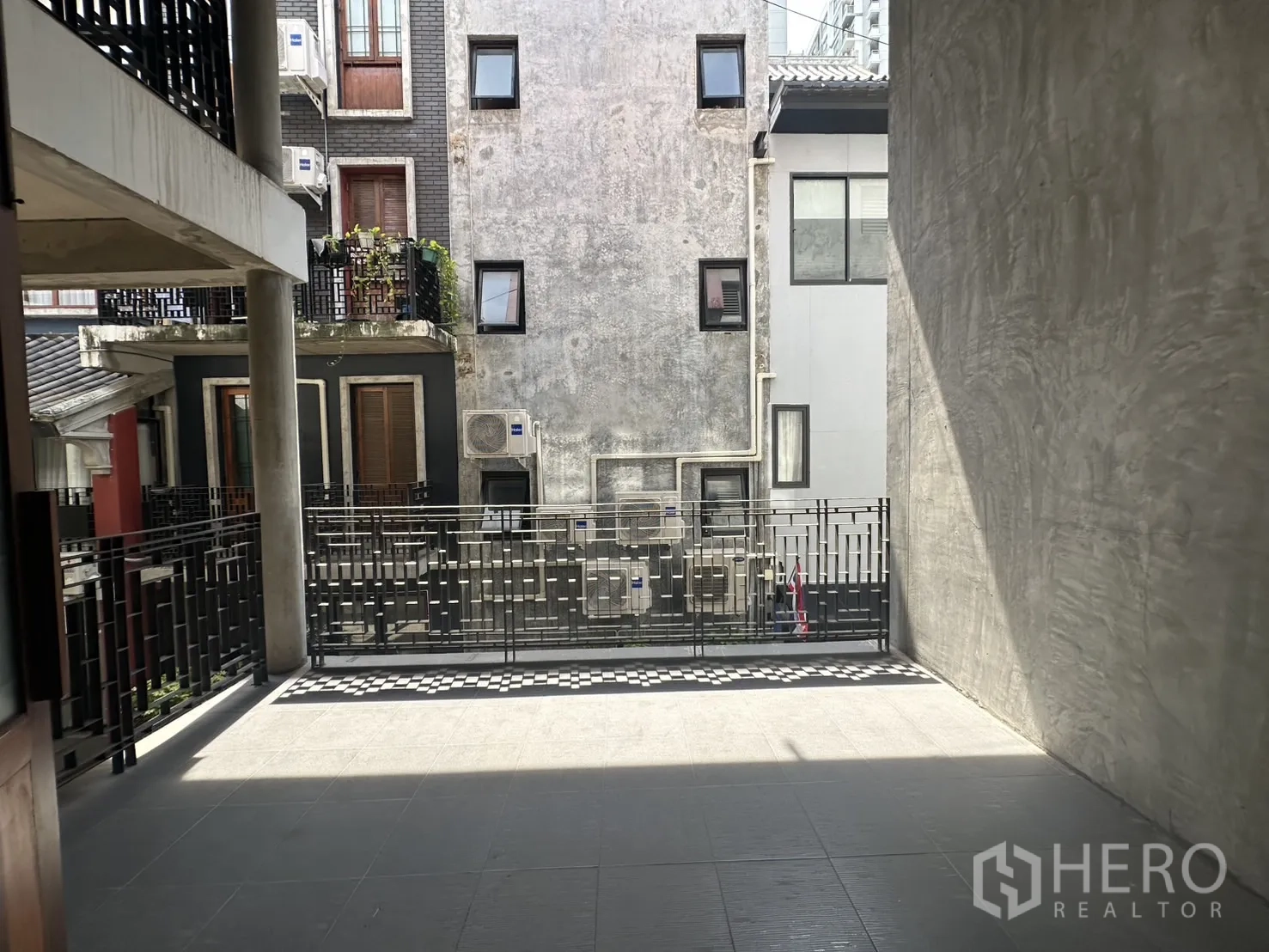 Home Office for rent in Pathum Wan, Bangkok - Covered terrace with tiled flooring and a geometric metal balustrade.
