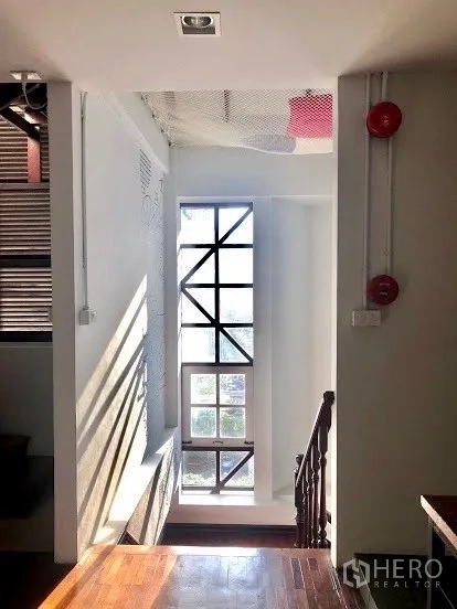 Shophouse for rent in Pathum Wan, Bangkok - Stairwell with a tall grid window bringing natural light onto timber steps.
