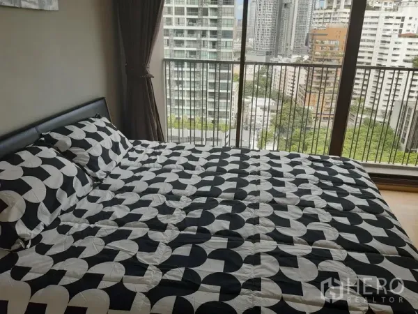 Condominium for rent in Bangkok - King-size bed beside large sliding glass doors opening to a high-floor city view.