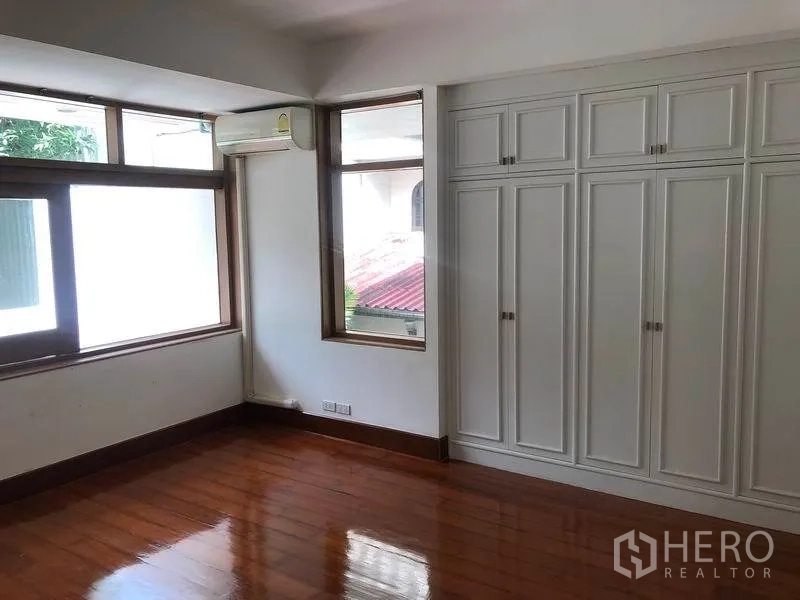 Detached House for rent in Watthana, Bangkok - Bedroom with built-in closets, air conditioning and polished wood floors.