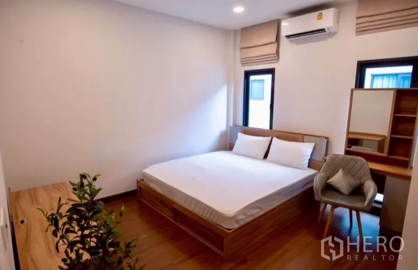 Detached House for rent in Bang Phli, Samut Prakan - Bright bedroom with wooden bed, small desk and air conditioning.