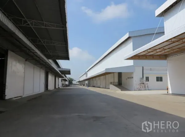 Warehouse for rent in Lopburi - Wide truck-access driveway between long warehouse blocks with protective canopies