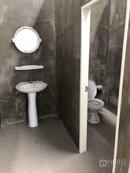 Factory for rent in Lat Lum Kaeo, Pathum Thani - Simple factory restroom with a pedestal sink and a toilet cubicle.