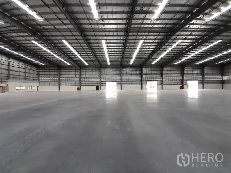 Factory for rent in Mueang Rayong, Rayong - Open industrial hall with multiple loading doors and continuous LED lighting.