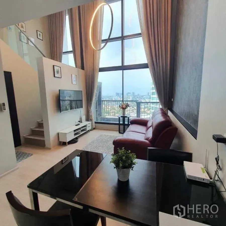 Condominium for rent in Khlong Toei, Bangkok - Another angle of the loft living area showing tall drapes, statement chandelier and skyline views.