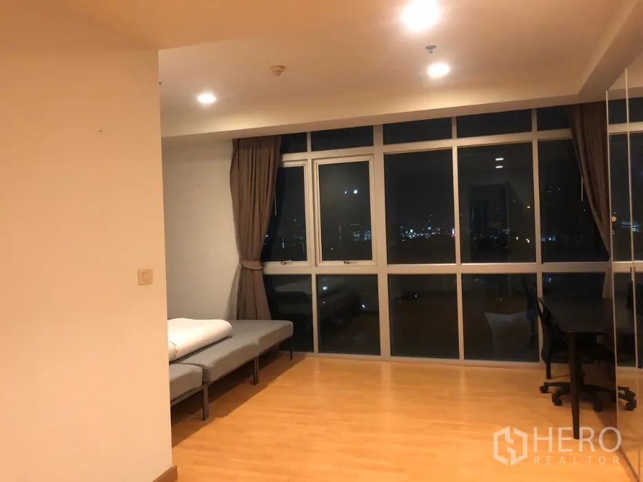Condominium for sale in Khlong Toei, Bangkok - Bright corner room with floor-to-ceiling windows, wood flooring and a study desk overlooking the city.
