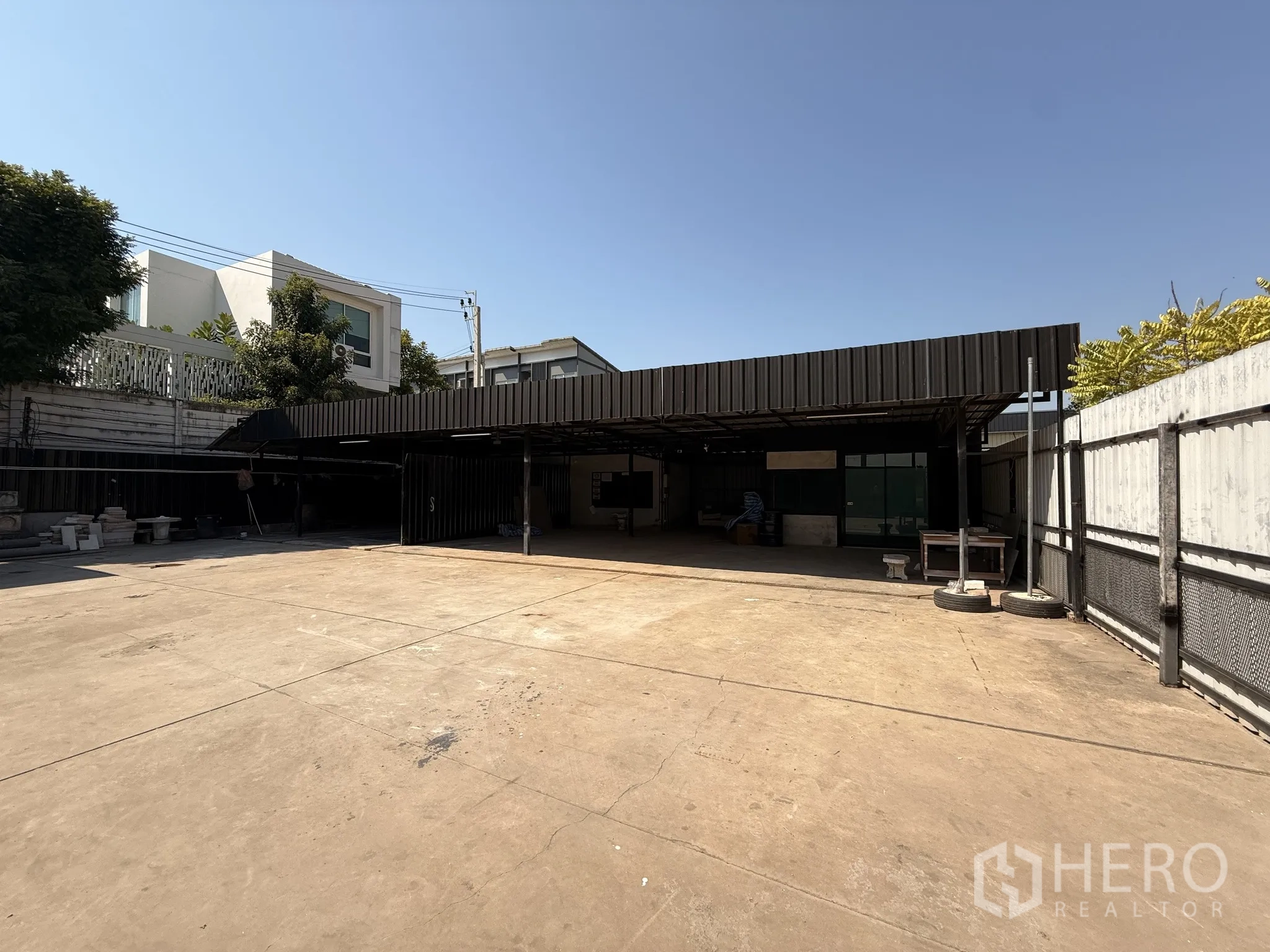 Warehouse for rent in Lat Krabang, Bangkok - Secure concrete courtyard with roofed work bays and perimeter fencing inside the warehouse compound.