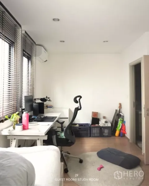 联排别墅 出租在Suan Luang, Bangkok - 采光充足的书房/客卧，长书桌、人机工学椅与百叶窗。