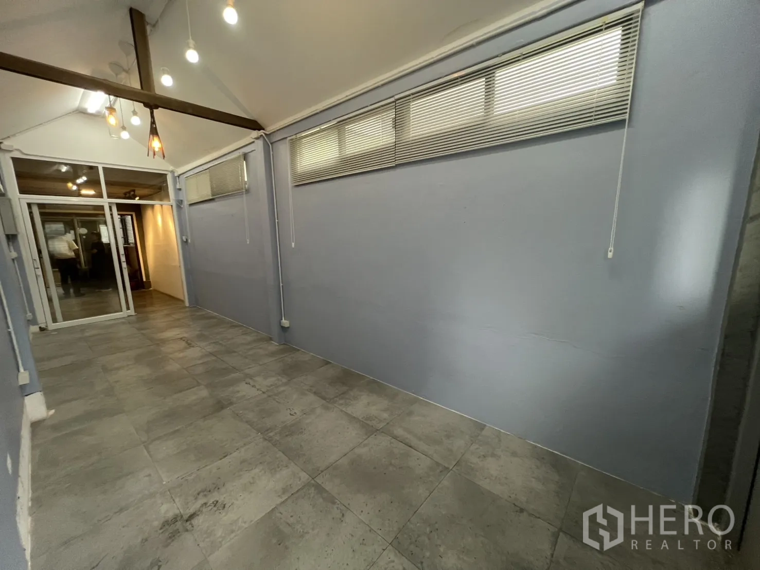 Retail Space for rent - Long rectangular retail room with gray floor tiles, blue walls and a sliding glass entry.
