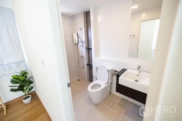 Detached House for sale in Prawet, Bangkok - Clean bathroom featuring a walk-in shower, toilet, sink and large mirror with neutral tiles.