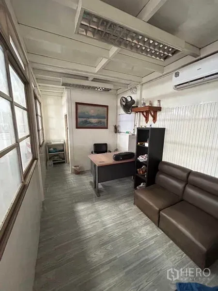 Warehouse for rent in Mueang Samut Prakan, Samut Prakan - Compact office inside the warehouse with desk, sofa, air-conditioner and shelving.