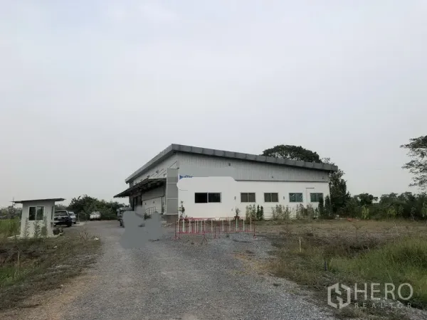 Factory for rent or sale in Wang Noi, Phra Nakhon Si Ayutthaya - Single-storey factory in Wang Noi with long gravel driveway, security booth and open green surroundings.