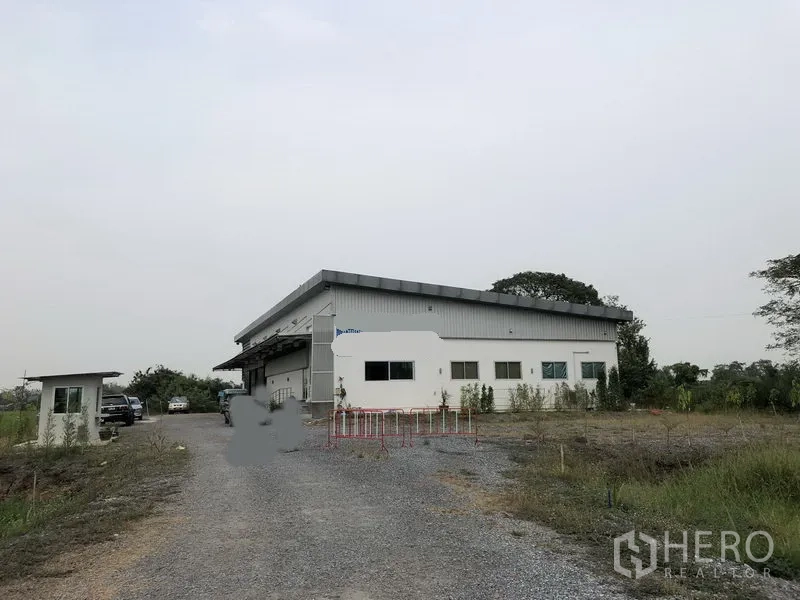Factory for rent or sale in Wang Noi, Phra Nakhon Si Ayutthaya - Single-storey factory in Wang Noi with long gravel driveway, security booth and open green surroundings.