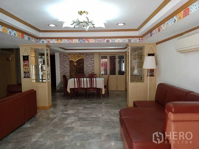 Townhouse for rent in Khlong Toei, Bangkok - Open-plan living and dining room with leather sofas and chandelier.