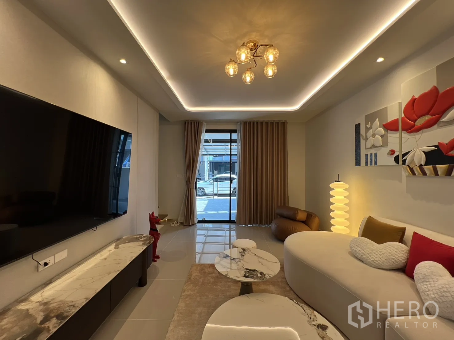 Townhouse for rent in Bang Phli, Samut Prakan - Living room facing the front with floor-to-ceiling curtains and a modern chandelier.