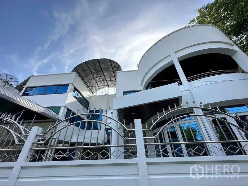 带办公室的家 出售 - 低角度外观，带弧形阳台与金属围栏的门禁家用办公楼。