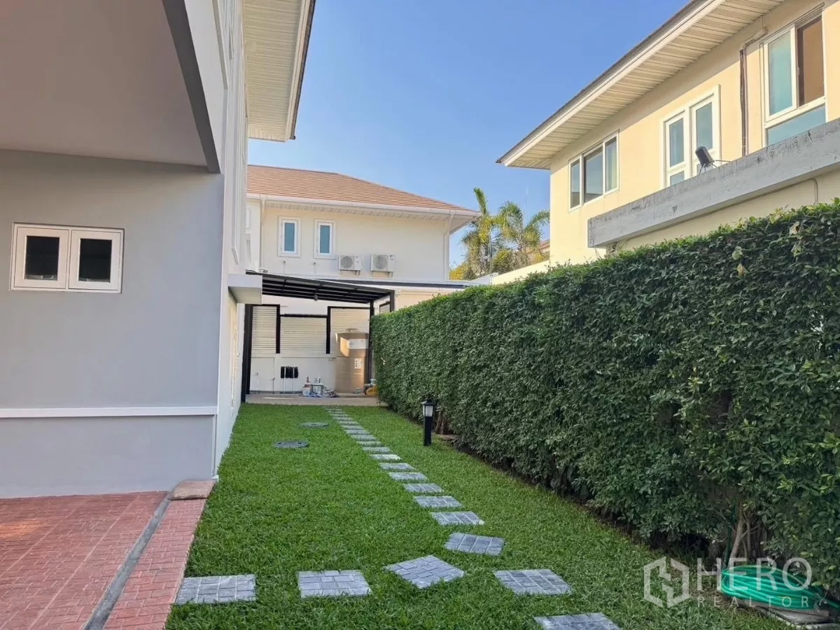 Detached House for rent or sale in Prawet, Bangkok - Side yard with long green lawn, privacy hedge and paved walkway to the service area.