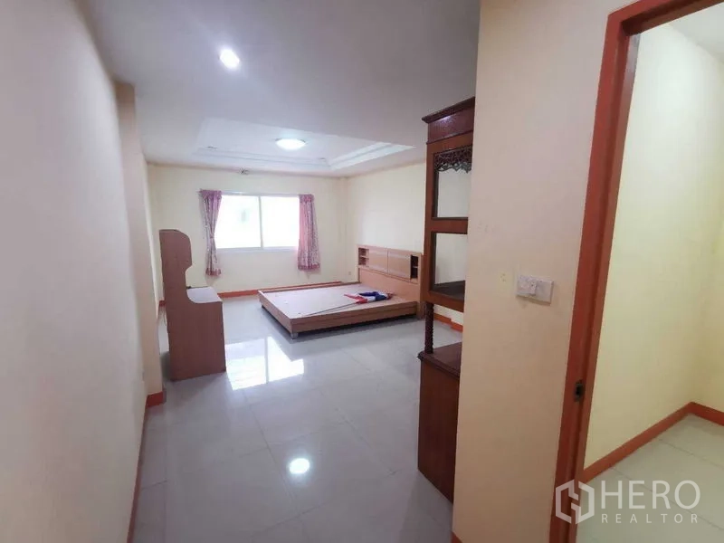 Shophouse for rent in Suan Luang, Bangkok - View of bedroom from hallway showing bed frame and window.