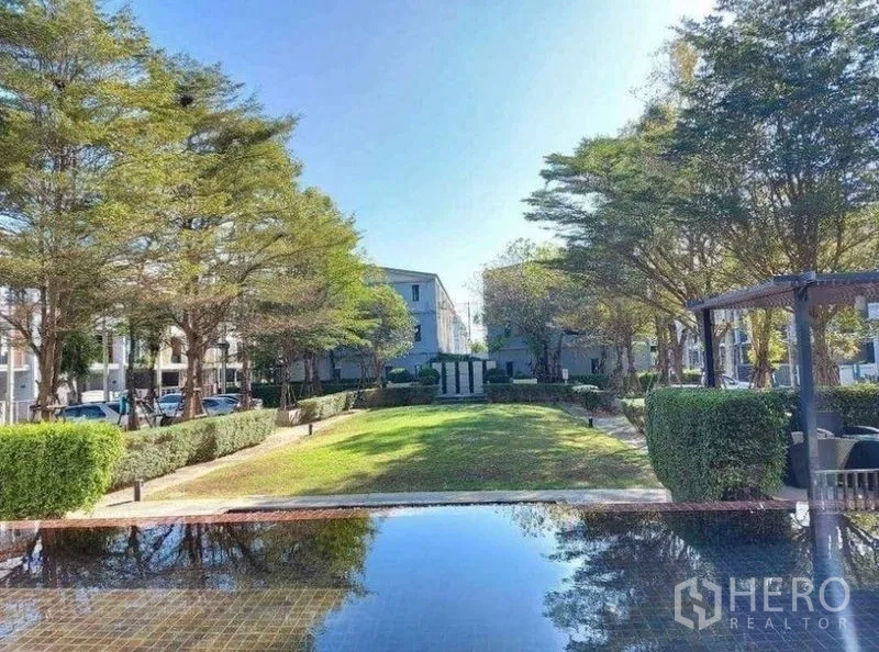 联排别墅 出租在Bang Phli, Samut Prakan - 社区花园设有镜面水景、修剪整齐的绿篱、乔木与亭子。