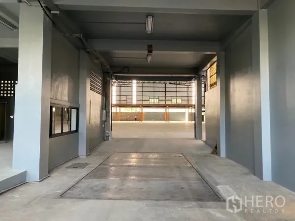 Warehouse for rent in Khlong Toei, Bangkok - Covered loading bay and drive-in access with overhead lighting leading into the main warehouse hall.