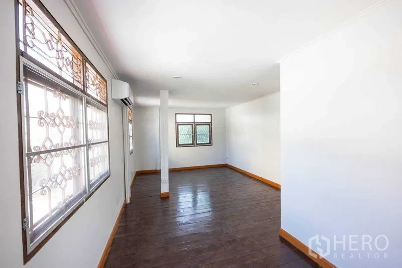 Home Office for rent in Watthana, Bangkok - Long upper floor workspace with wood floors and windows with decorative security grilles.