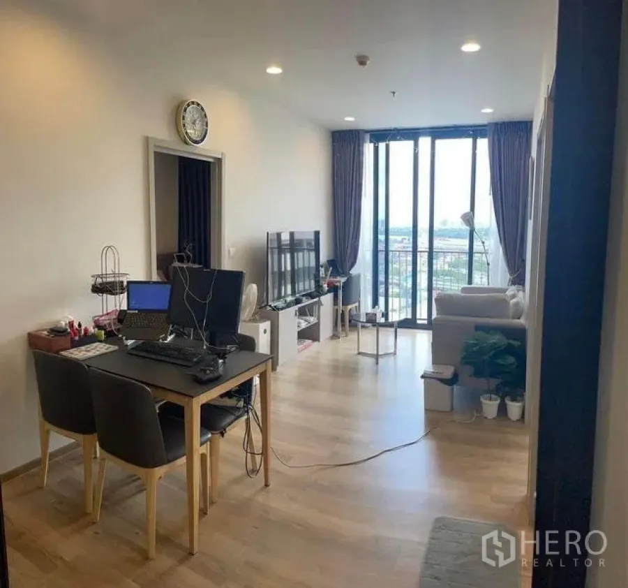 Condominium for rent in Khlong Toei, Bangkok - Living-dining area with TV console and large sliding doors opening to the balcony and city view.