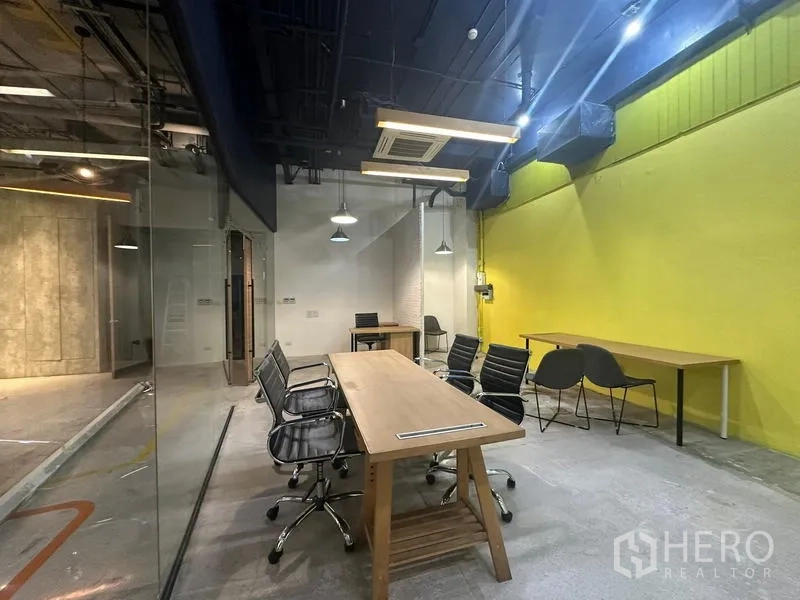 Office Space for rent - Meeting zone with long table, pendant lights and a bright yellow feature wall.