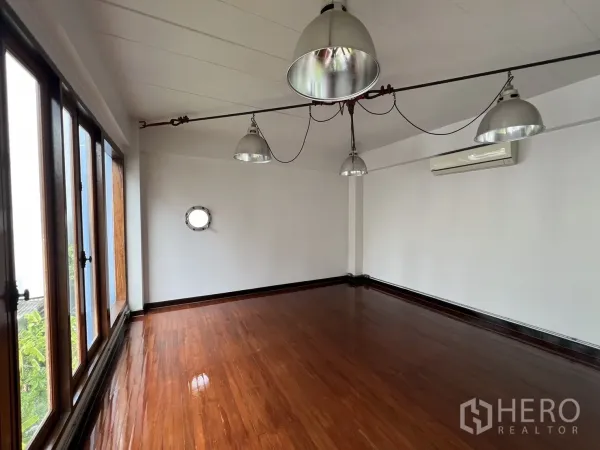 Home Office for rent in Watthana, Bangkok - Compact office room featuring wood floors, large windows, air-conditioning and hanging lights.
